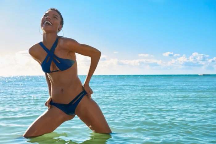 Iyonna Fairbanks stands knee-deep in the ocean in a deep blue bikini set.